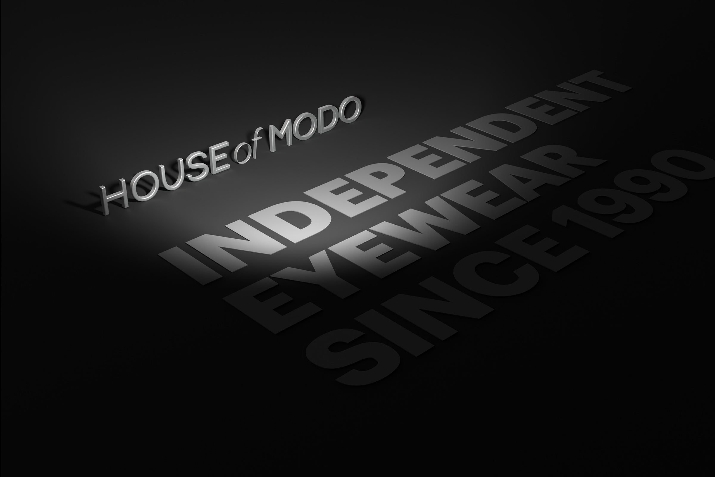 3D HOUSE of MODO logo with ‘Independent Eyewear Since 1990’ text on dark grey surface – premium independent eyewear branding.